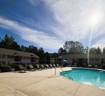 A sunny day at the pool with chairs and umbrellas.
